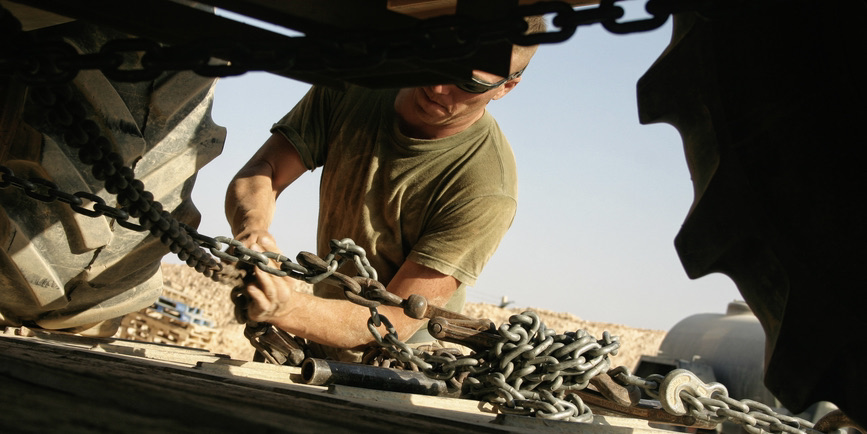 A color photograph of an Army mechanic working on a truck.